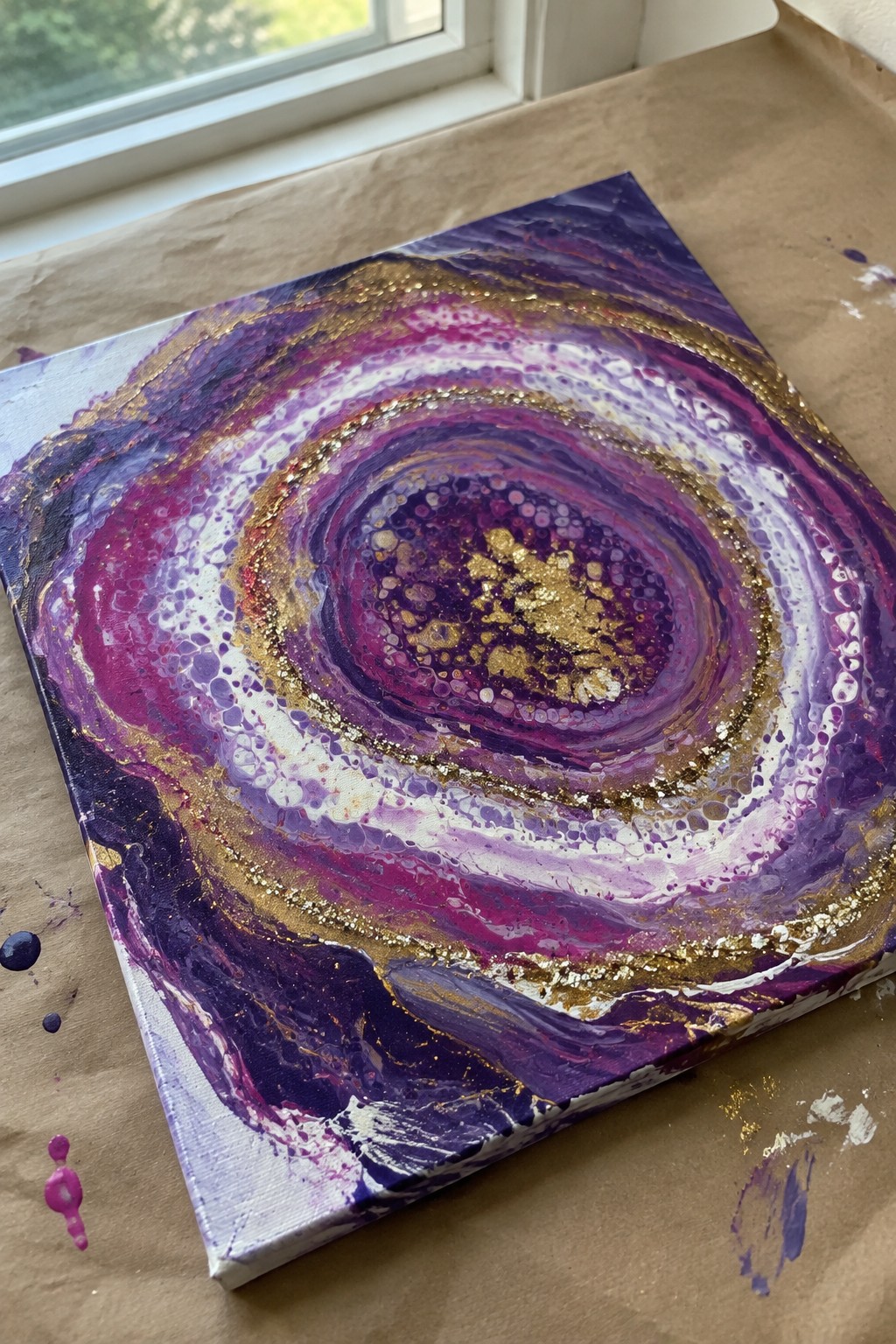 Abstract fluid art canvas with swirling purple, pink, white, and gold concentric circles