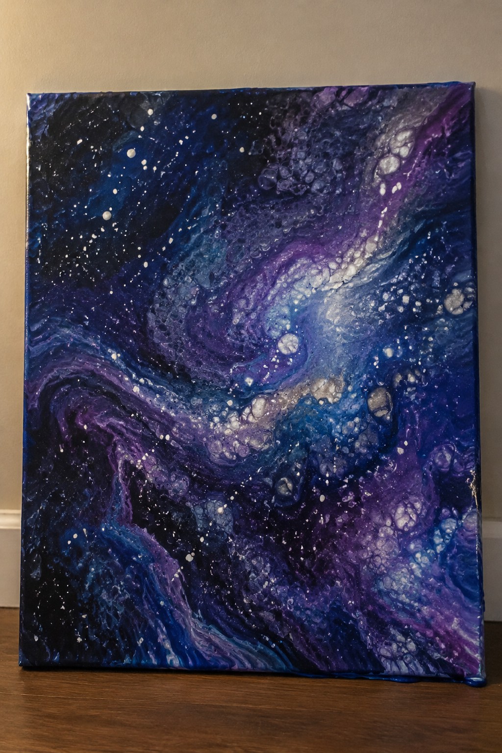 Abstract fluid art painting of swirling blue-purple galaxy with white star dots