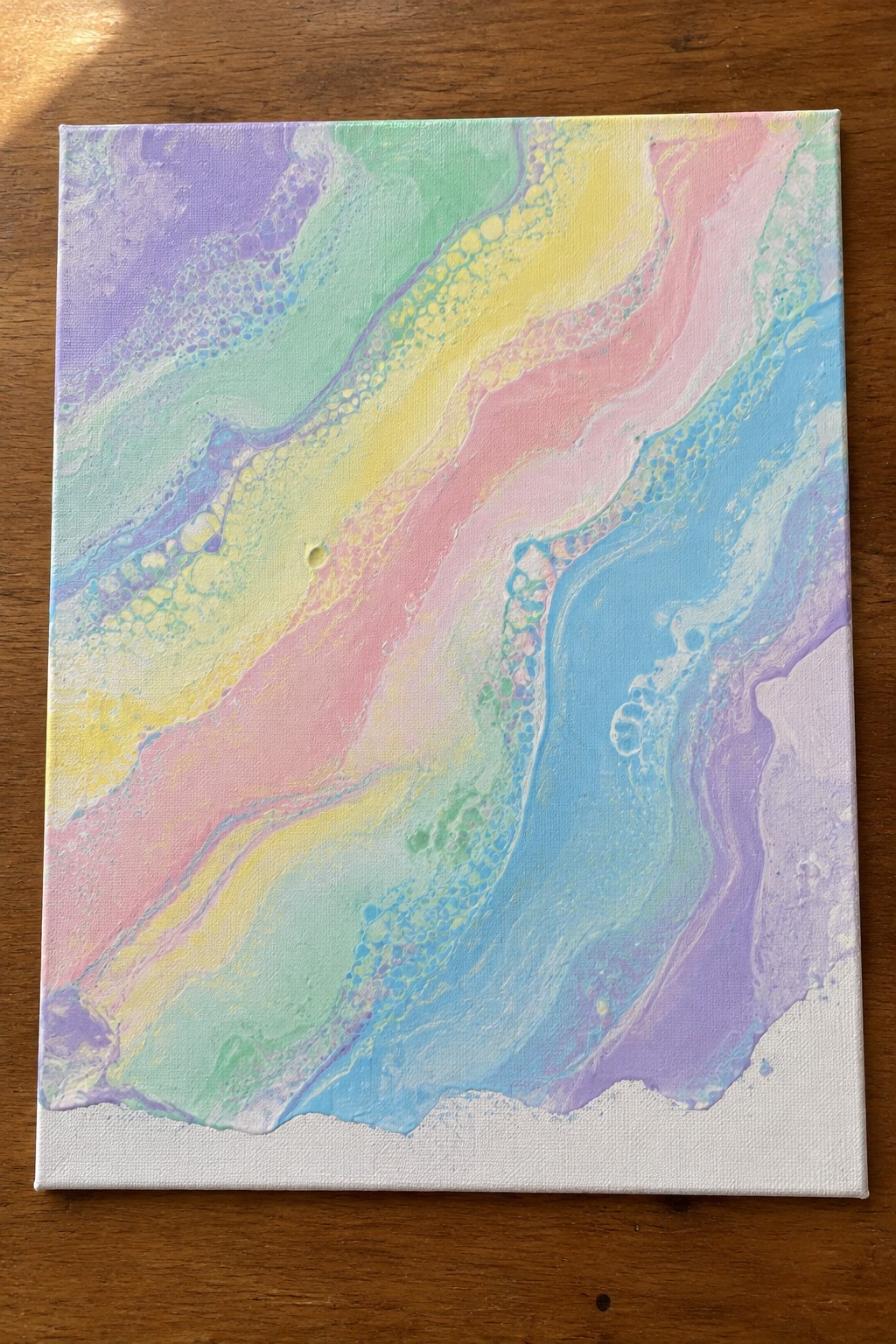 Abstract fluid art with pastel rainbow swirls, bubbles, and cells on canvas over wood