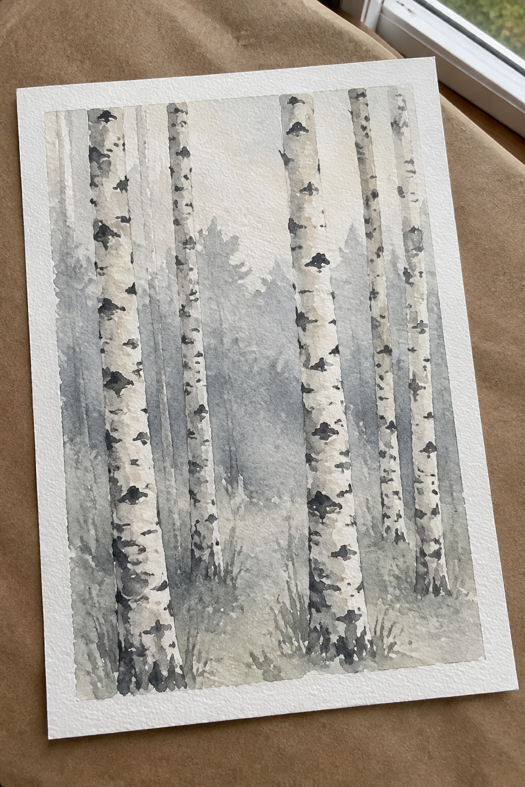 Watercolor painting of birch trunks with black markings amid misty gray forest foliage