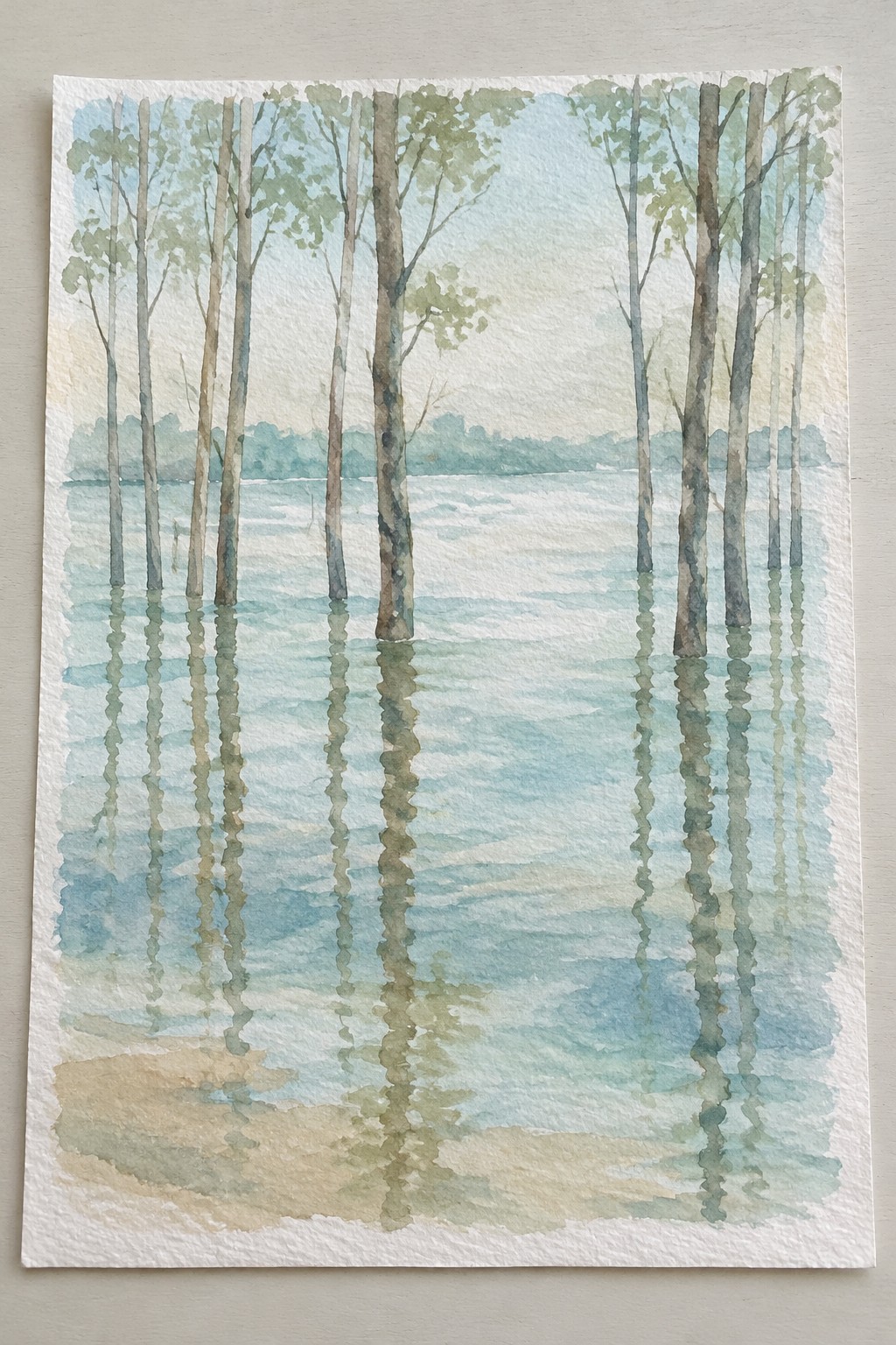 Watercolor of tall trees reflected in calm misty blue-green water with sandy foreground