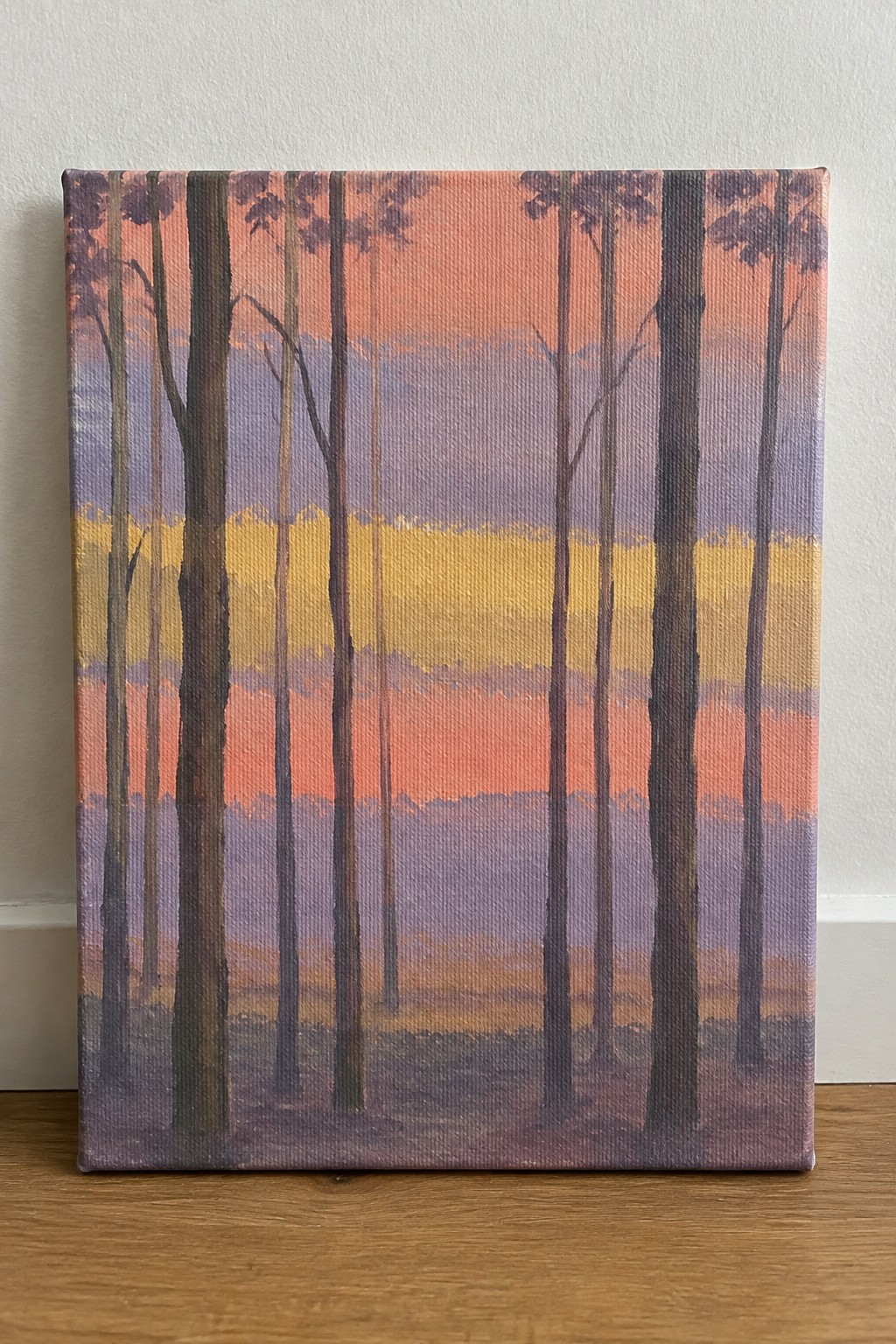 Tall dark trees silhouetted against horizontal bands of orange, yellow, and purple sunset colors