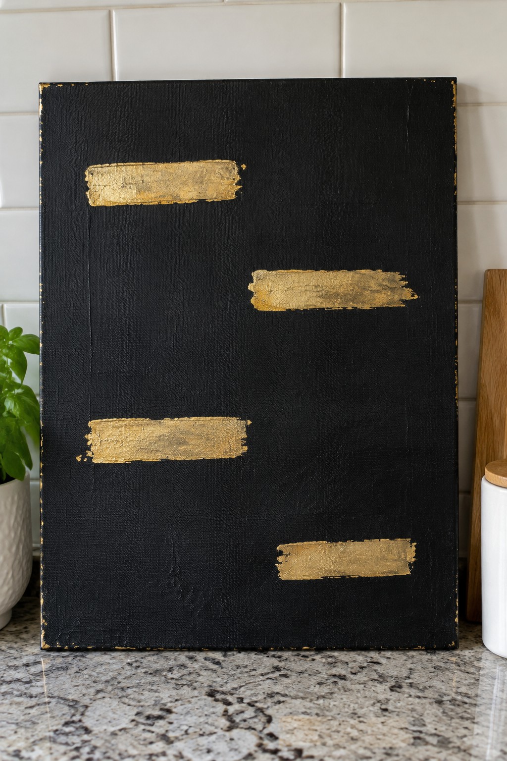 Black canvas with four scattered gold brush strokes on kitchen counter