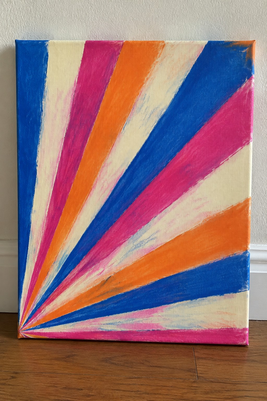 A canvas with bold radiating stripes in blue, pink, orange, and cream fanning out from the bottom left corner.