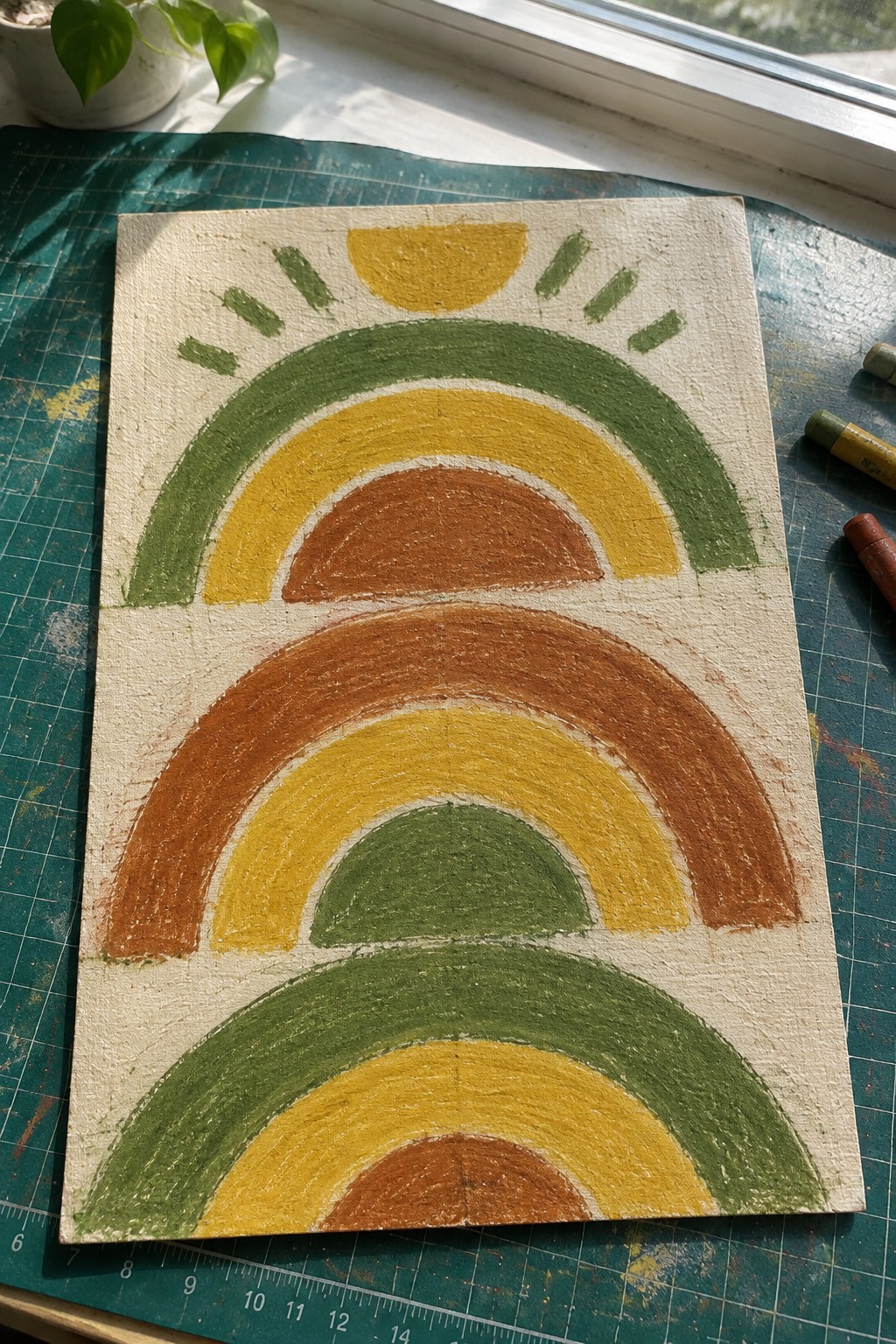 Earth-toned rainbow painting with green yellow orange arches and sun on canvas