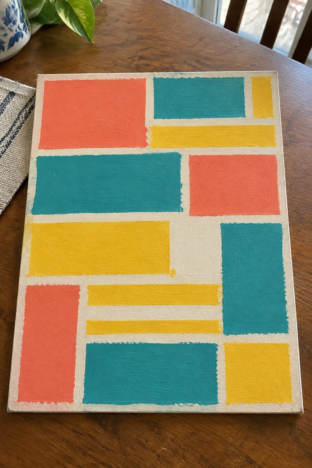 Abstract geometric painting with coral, teal, and yellow rectangles on canvas
