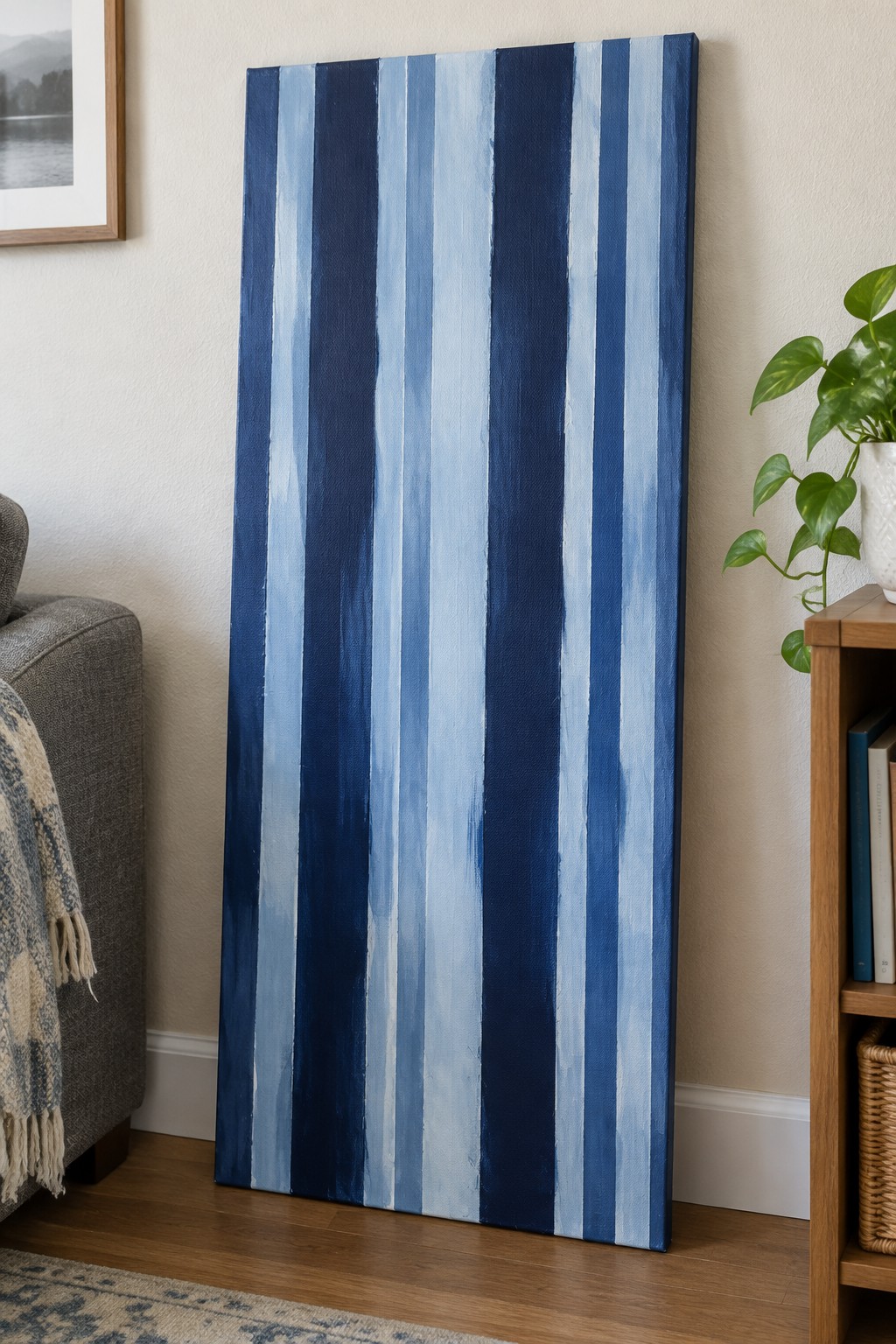 Tall blue-and-white striped canvas leaning against wall beside wooden bookshelf