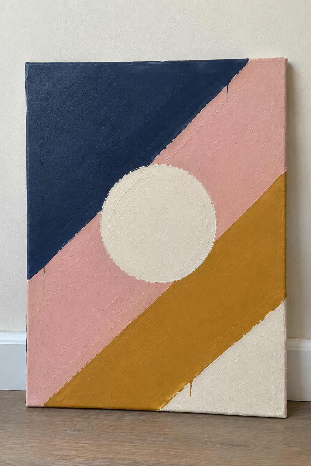 Abstract painting with diagonal navy, pink, mustard, and cream sections and a large off-white circle overlapping the pink band.