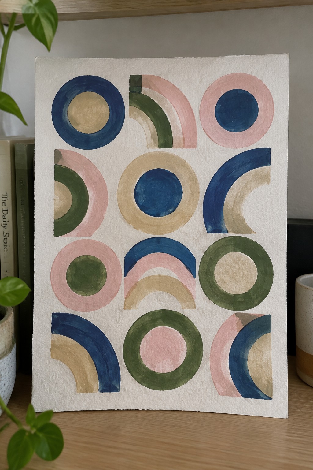 Abstract watercolor artwork with colorful concentric circles and arcs in blue, pink, green.