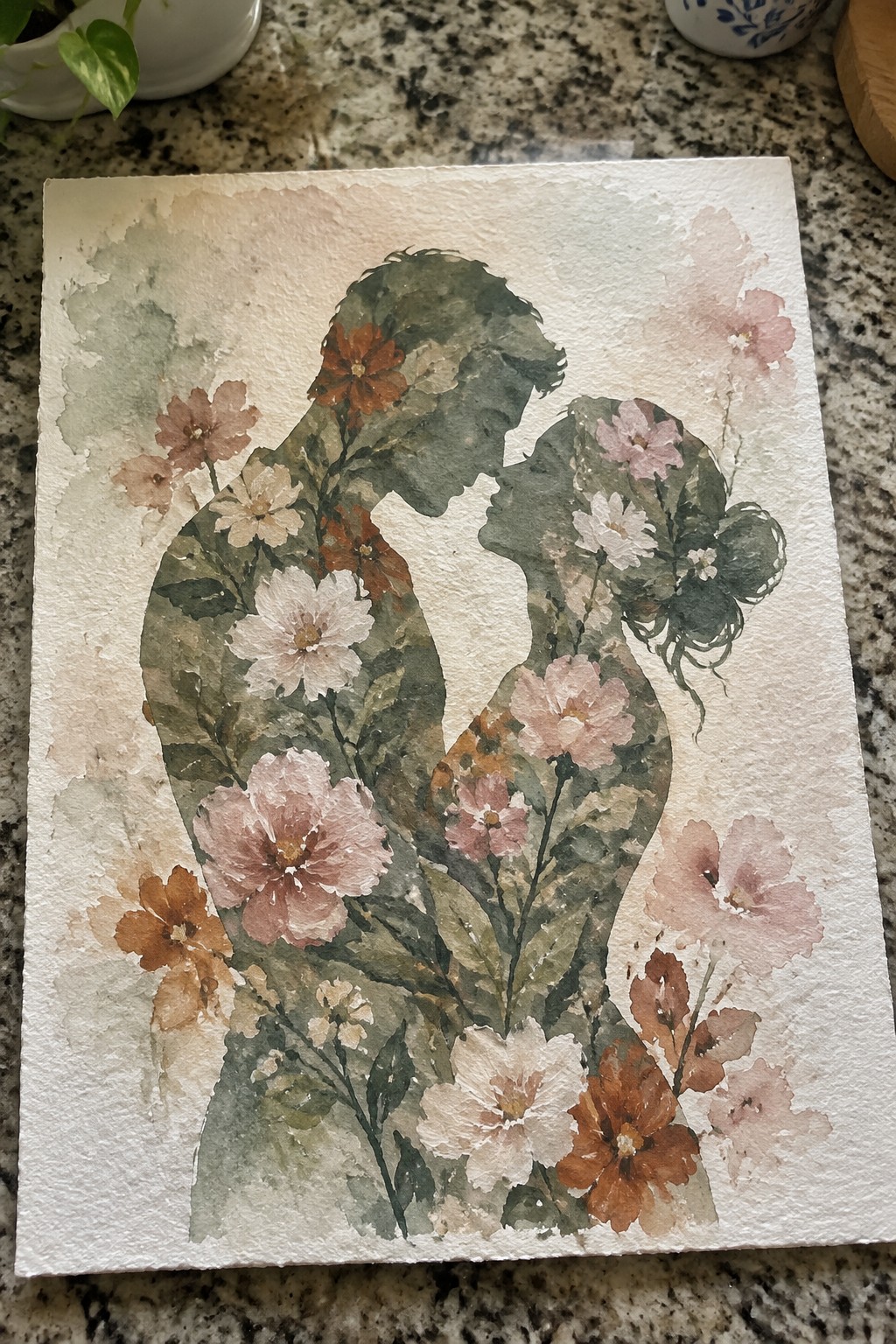 Watercolor silhouettes of a couple filled with pink, white, and brown flowers on textured paper