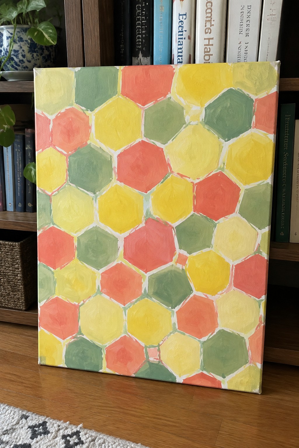Colorful hexagonal canvas painting leaning against a bookshelf with books