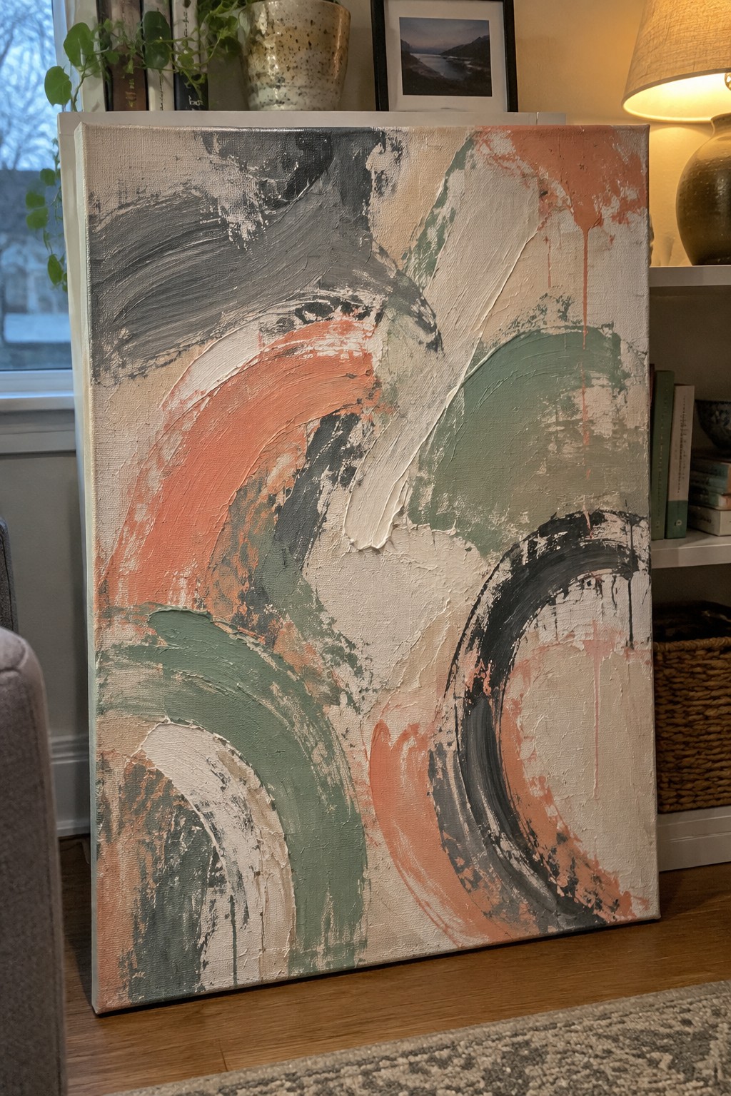 Abstract canvas with bold swirling orange, green, and black brushstrokes in living room