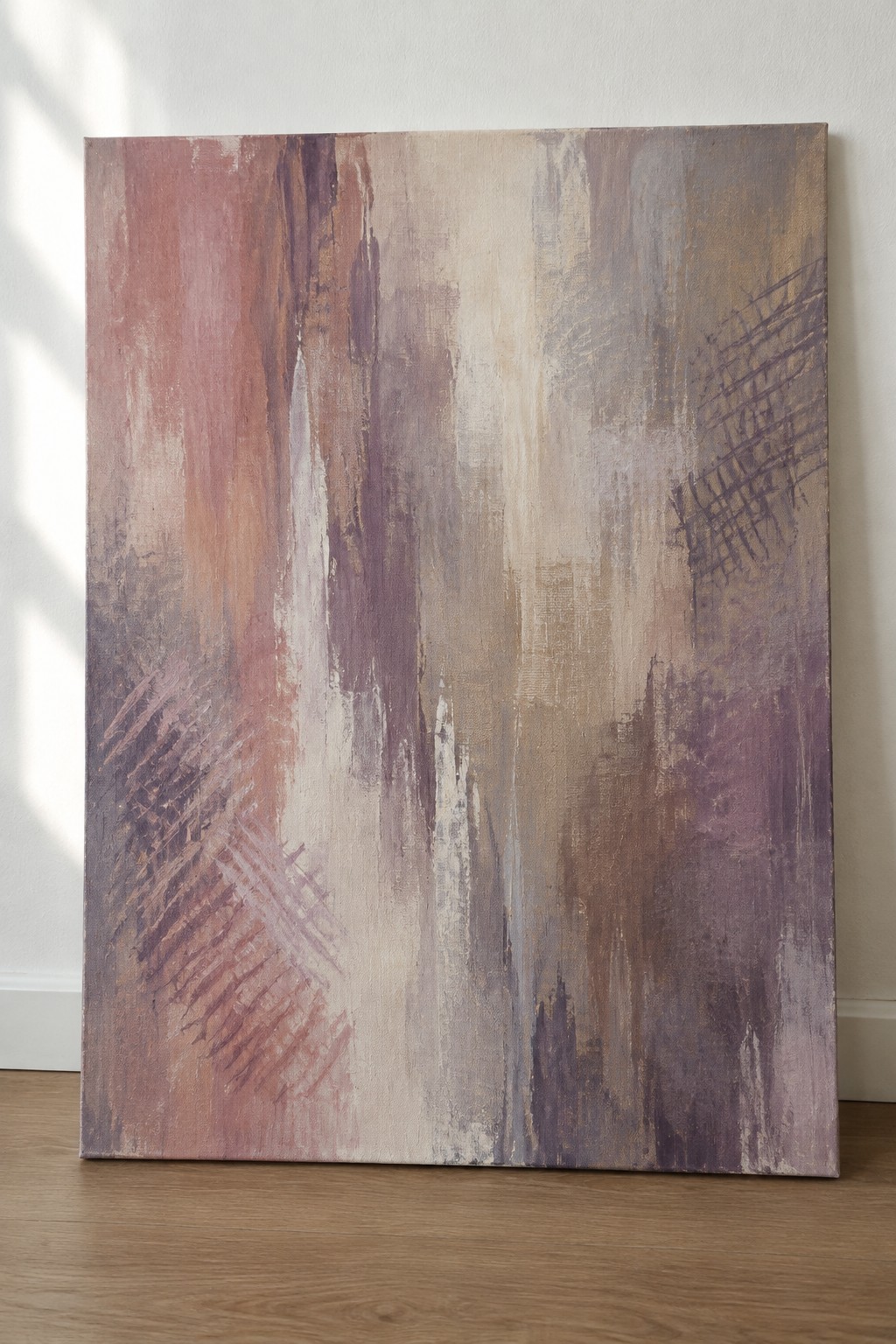 Abstract painting with pink, purple, and beige brushstrokes on canvas against white wall.
