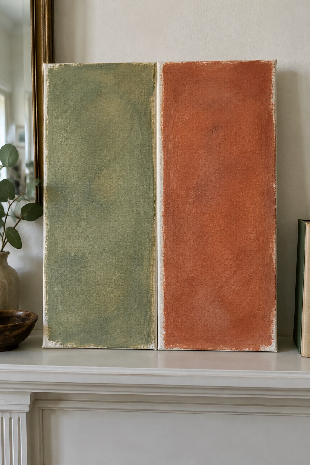 Two abstract paintings in sage green and rust orange on white mantelpiece