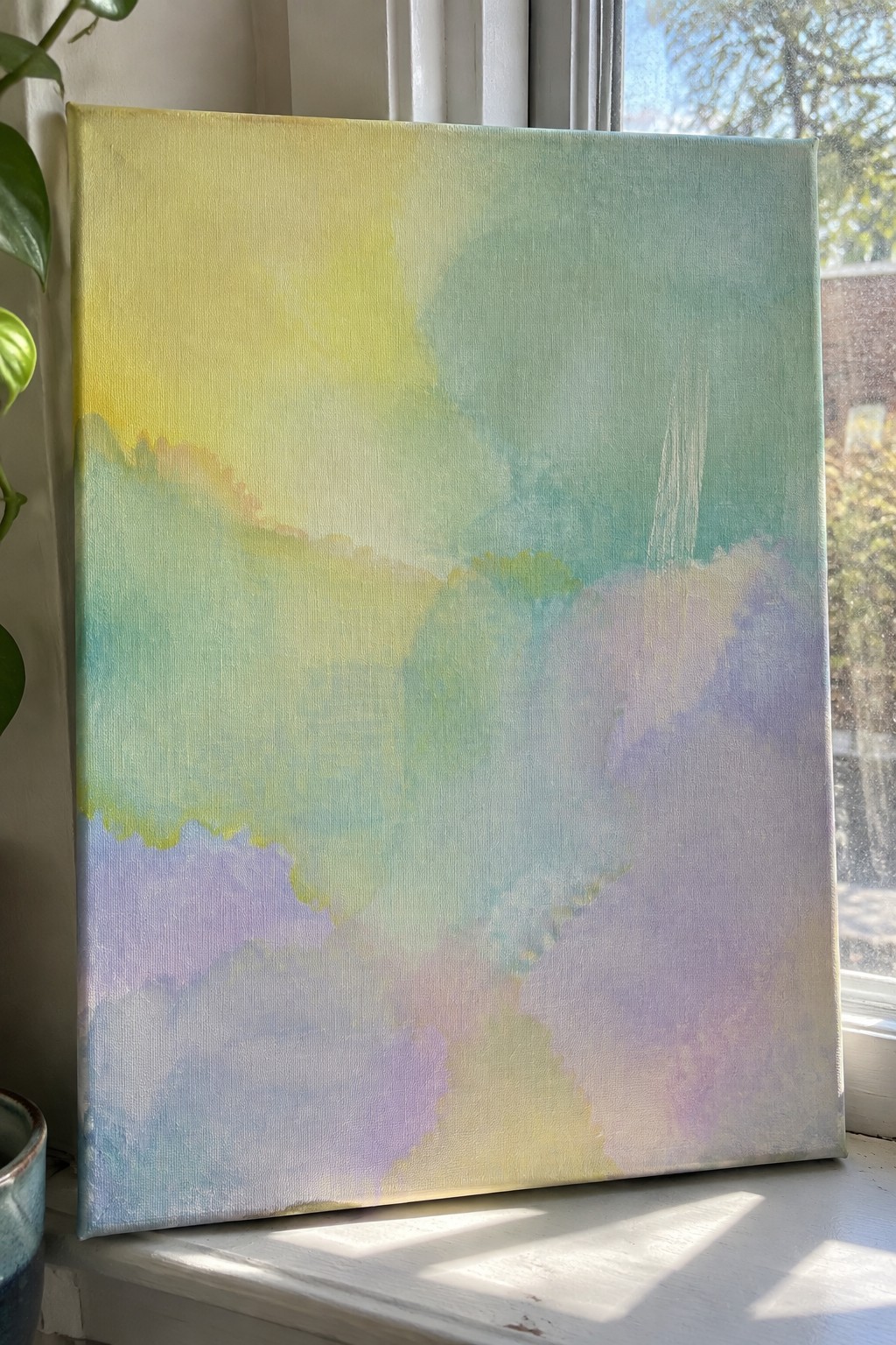 Abstract watercolor painting in soft yellow green blue and purple on sunny windowsill