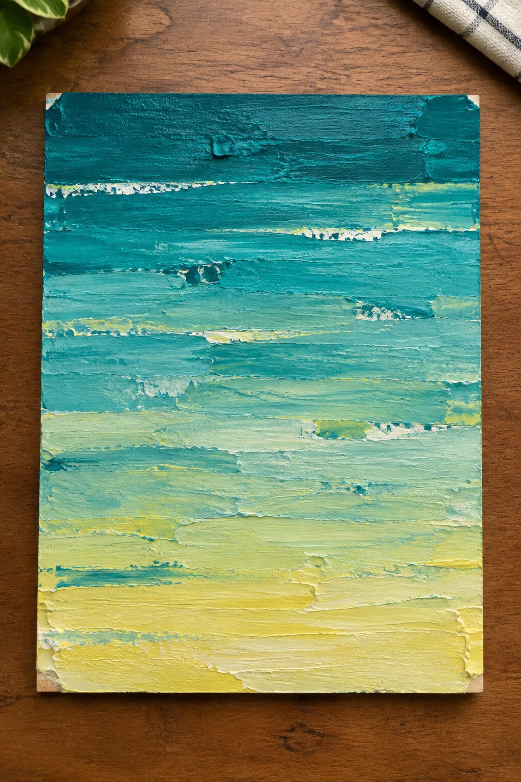 Thickly textured abstract painting with horizontal strokes blending teal blue green to yellow on wood