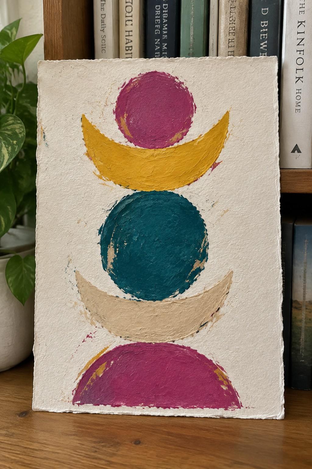 Abstract painting with stacked magenta circles, yellow and beige crescents, teal orb on textured white canvas