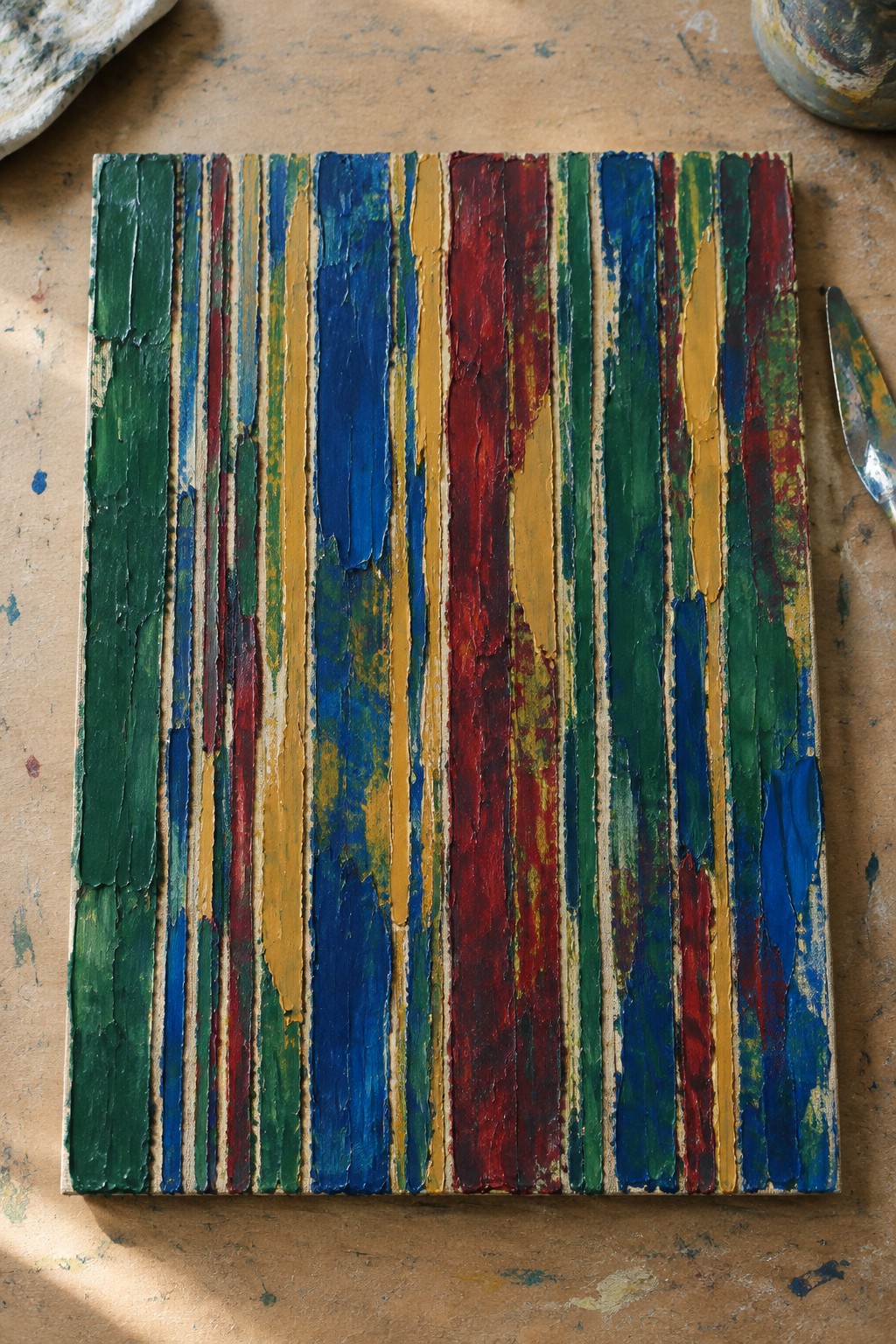 Abstract canvas with thick vertical stripes of green, blue, red, and yellow paint
