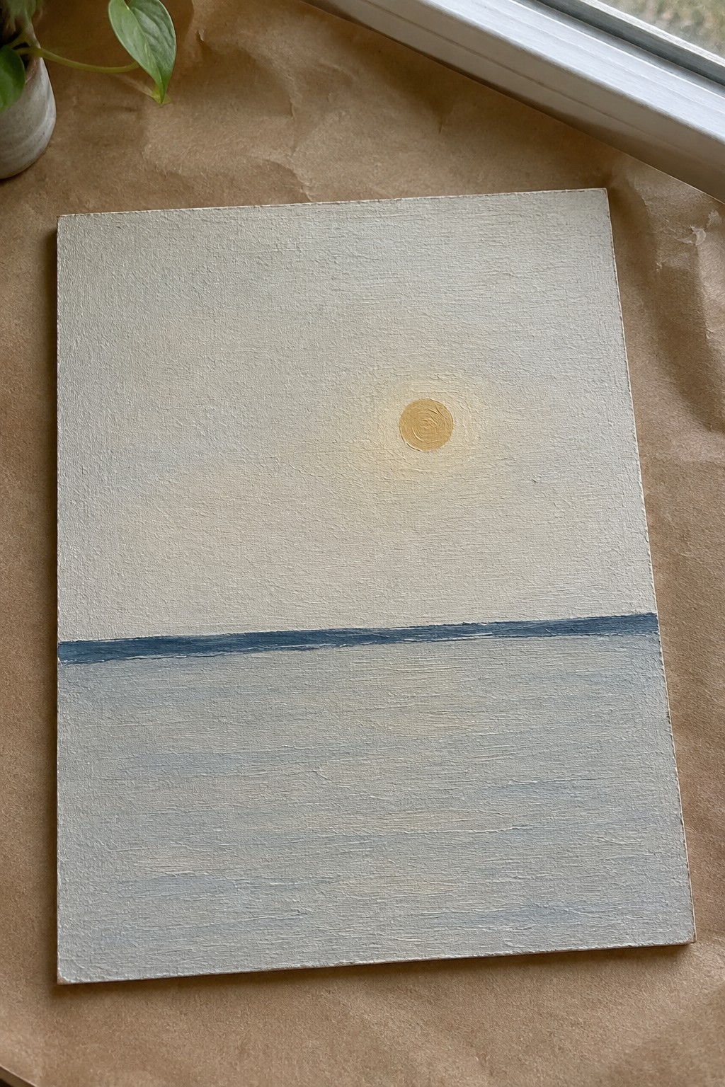 Minimalist painting with golden sun above thin blue line on beige and gray canvas