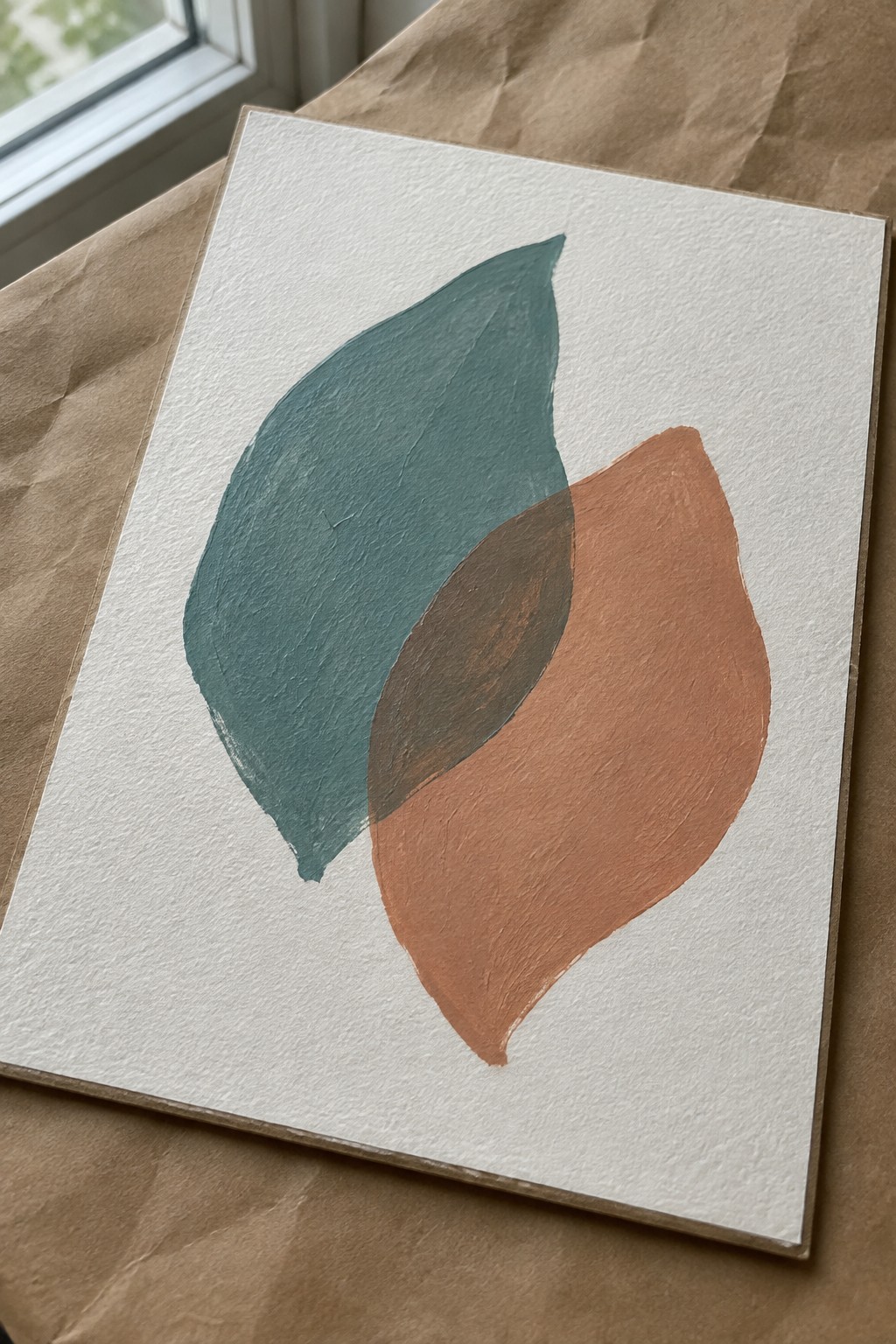 Abstract painting of overlapping teal and terracotta leaf shapes on white paper
