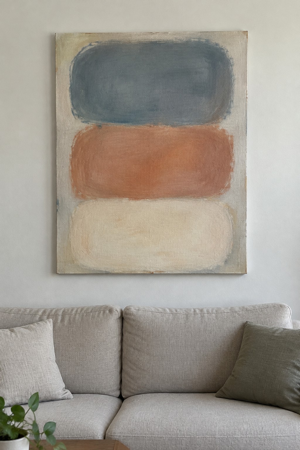 Abstract painting with blue-gray, terracotta, and cream horizontal shapes above beige sofa