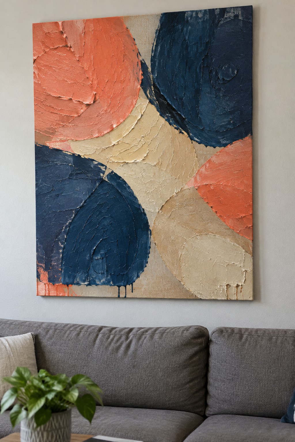 Abstract painting with coral, navy, and beige textures above gray sofa and potted plant