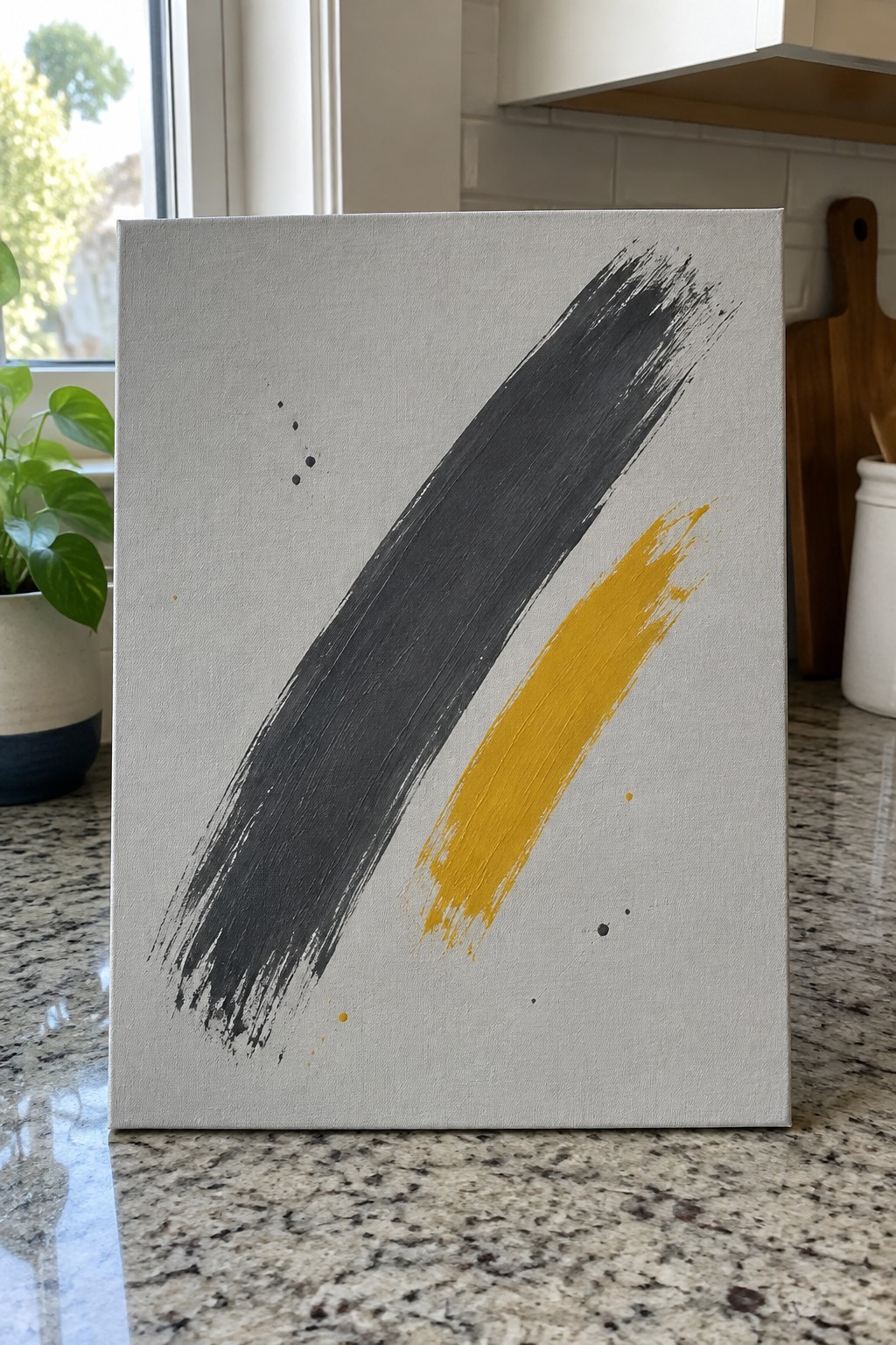 Canvas with bold gray and yellow brushstrokes on marble kitchen counter
