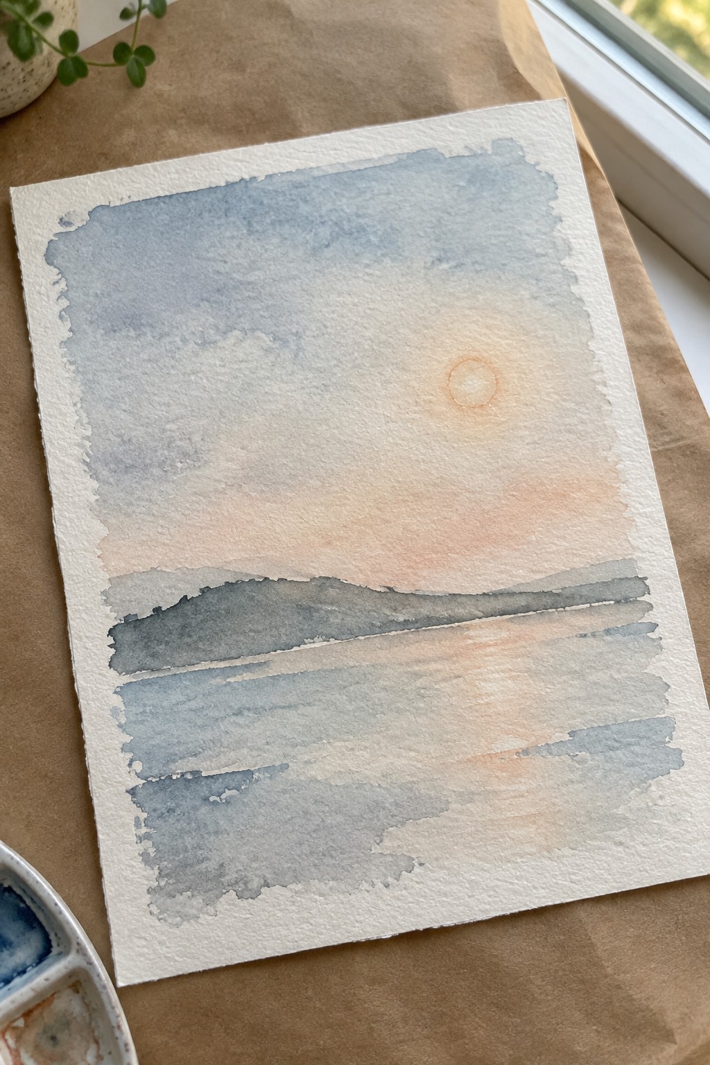 Watercolor painting of pale sun in blue-peach sky above layered gray-blue washes
