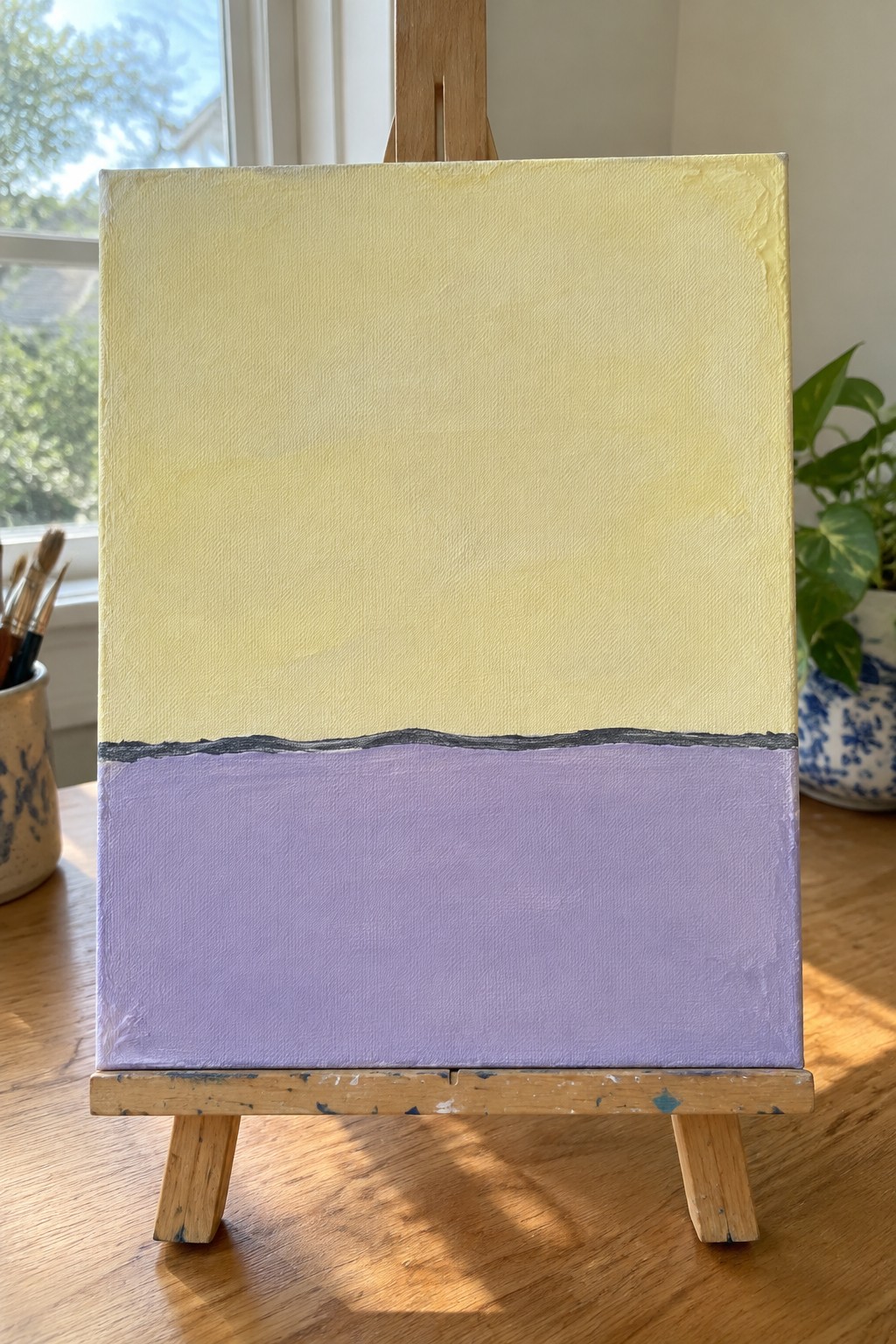 Yellow and purple abstract painting with wavy black line on wooden easel