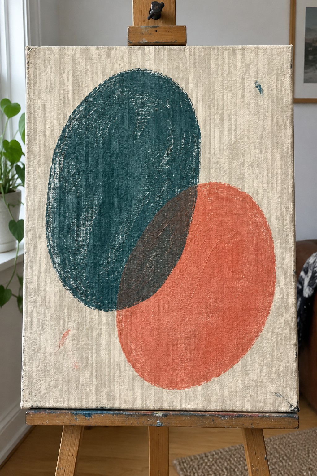 Abstract painting of overlapping teal and coral circles on wooden easel
