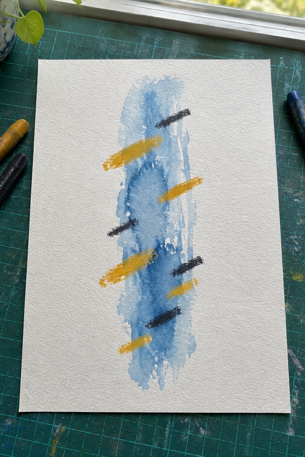 White paper with vertical blue watercolor wash and yellow black crayon strokes