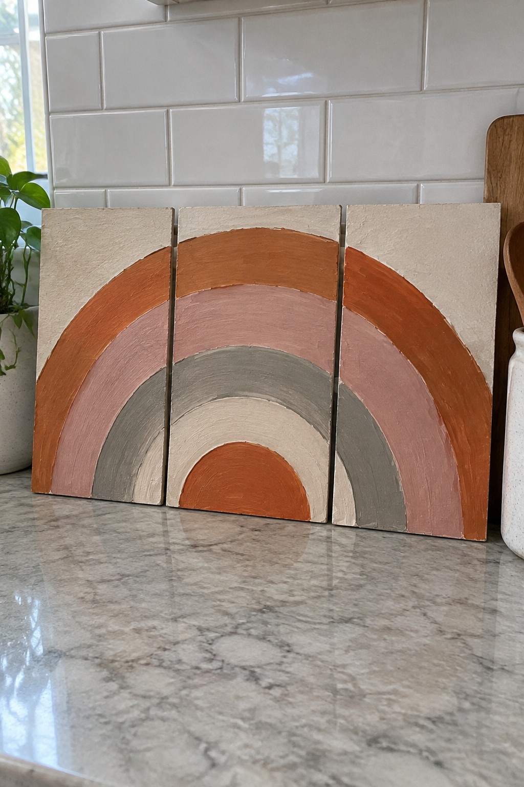 Three wooden panels with split rainbow arches in earthy tones on marble counter