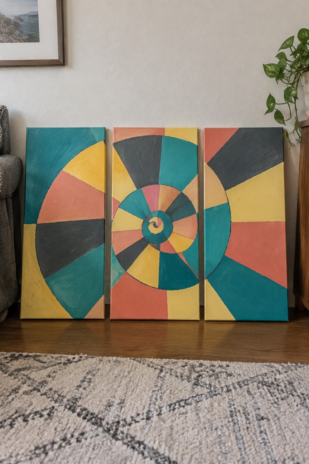 Three colorful abstract paintings with spiral designs leaning against a wall.