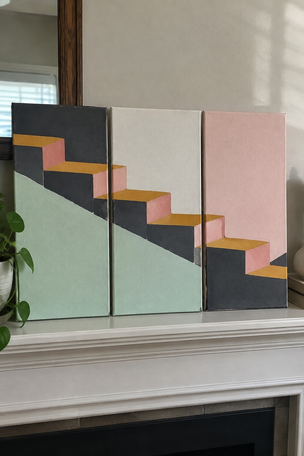 Three canvas paintings side by side showing a continuous geometric staircase in black, pink, and yellow blocks against mint green, off-white, and pink backgrounds.
