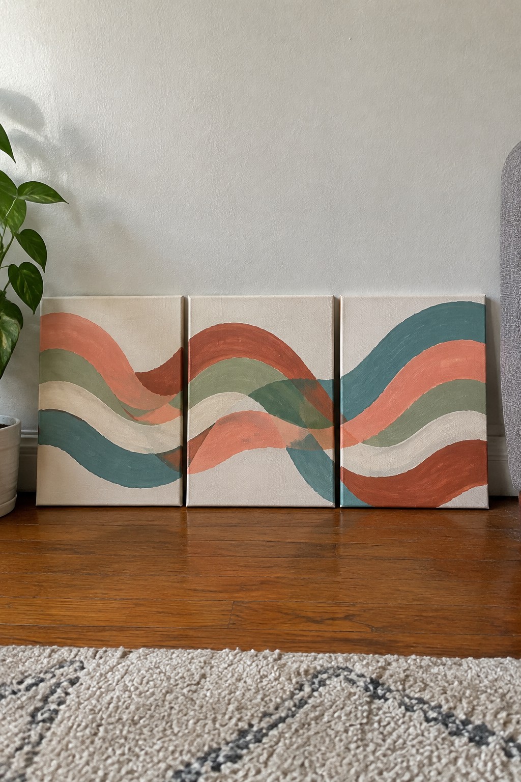 Three abstract wave paintings in coral, teal and sage on canvases