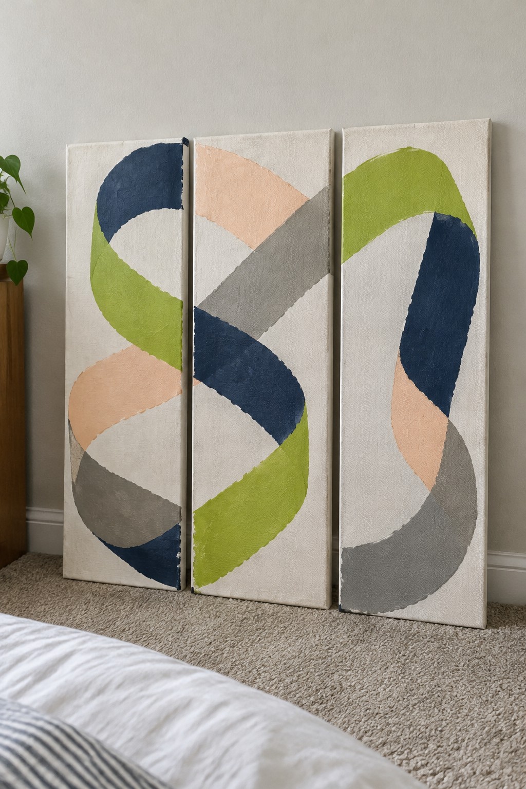 Three vertical canvases show abstract twisting ribbons in navy blue, lime green, peach, and gray against an off-white background.