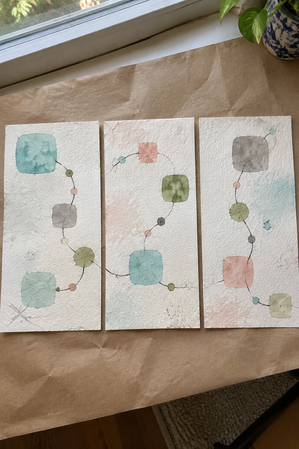 Three abstract watercolor artworks with connected squares and circles in muted tones.