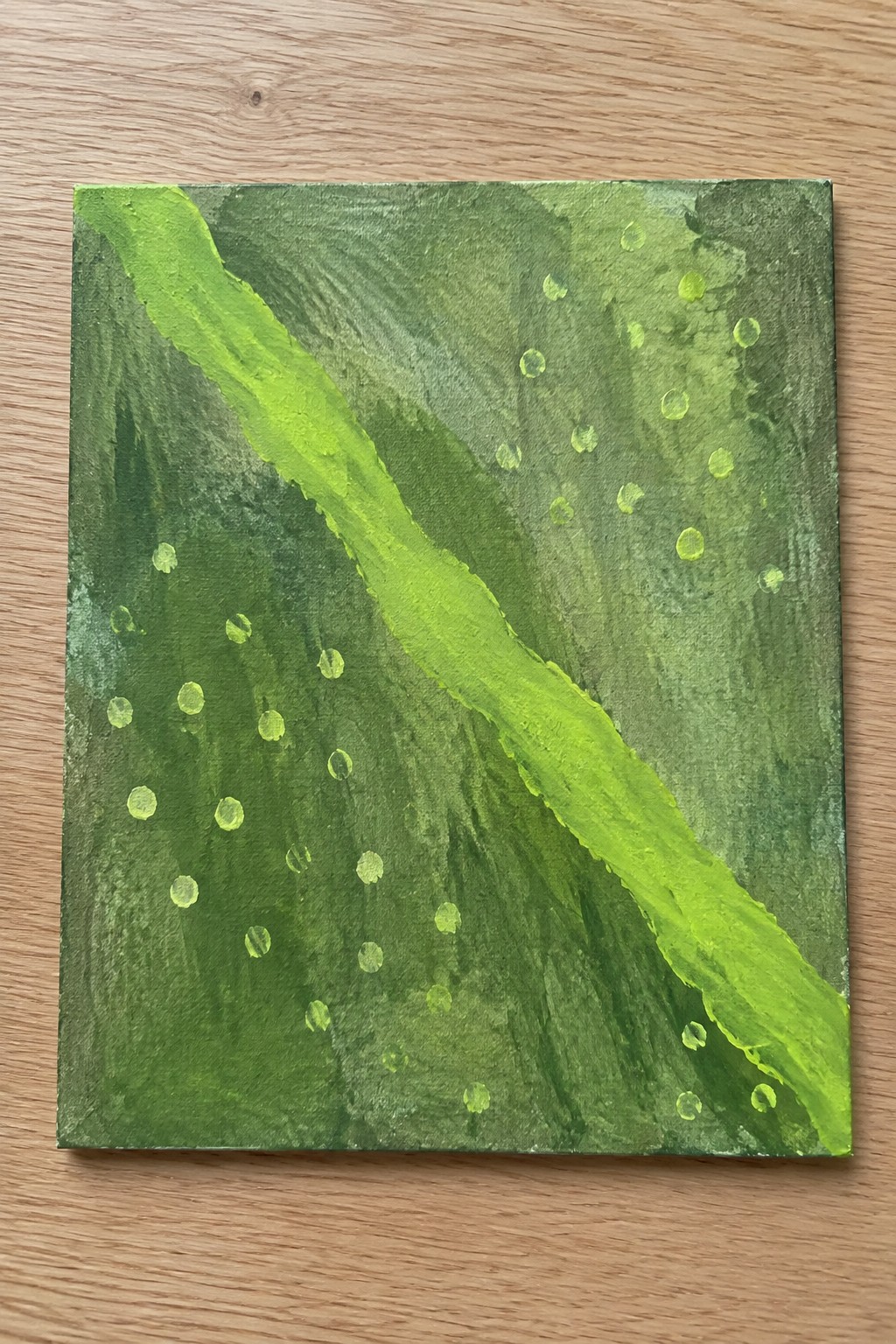 A square abstract painting with layered shades of green, a bright lime diagonal stroke, and scattered light green dots on a textured background.