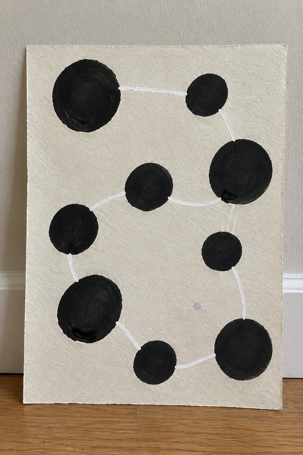 Black circles of varying sizes linked by white lines on textured paper