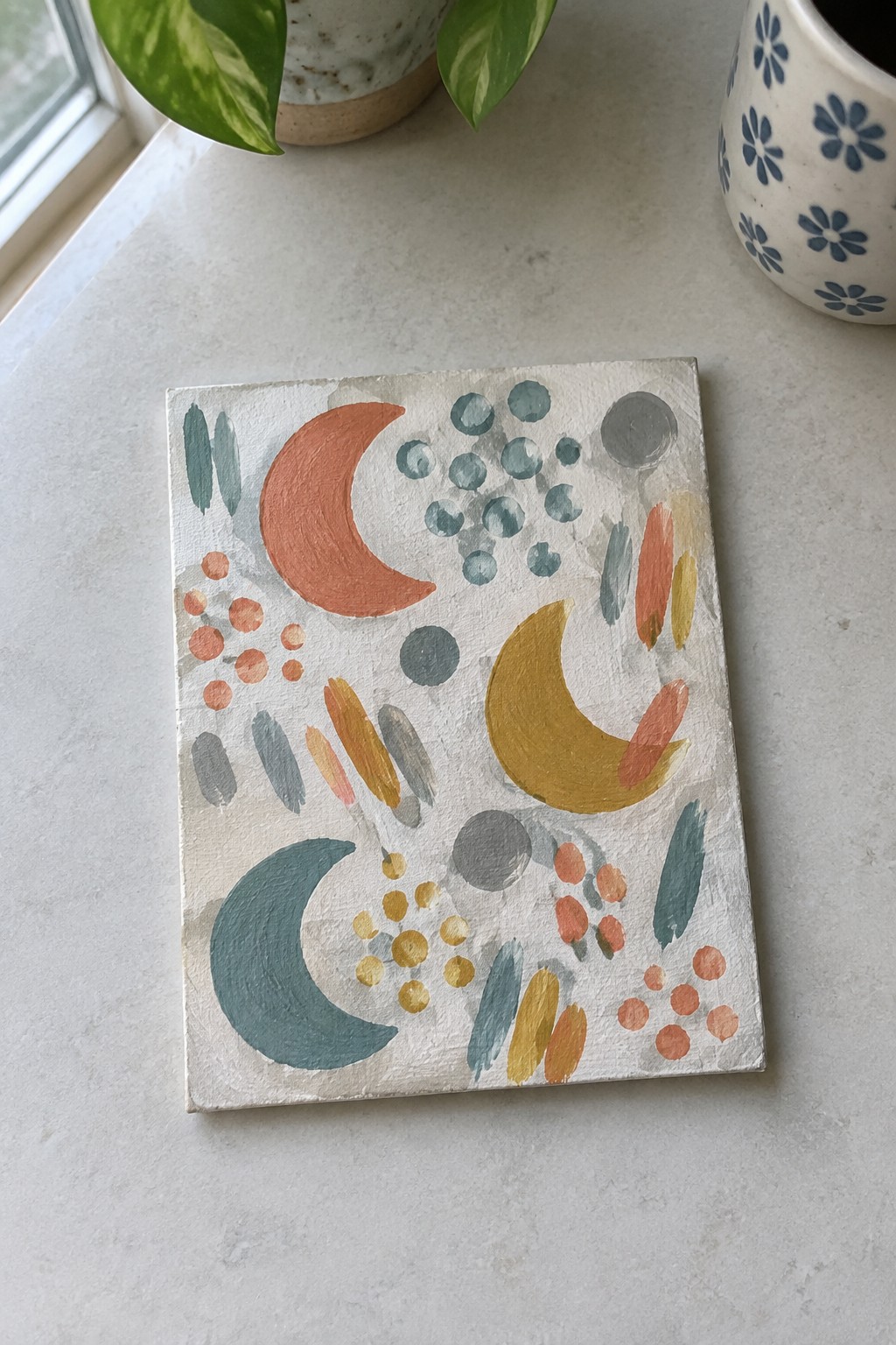 Abstract painting with colorful crescent moons, dots, and shapes on white canvas
