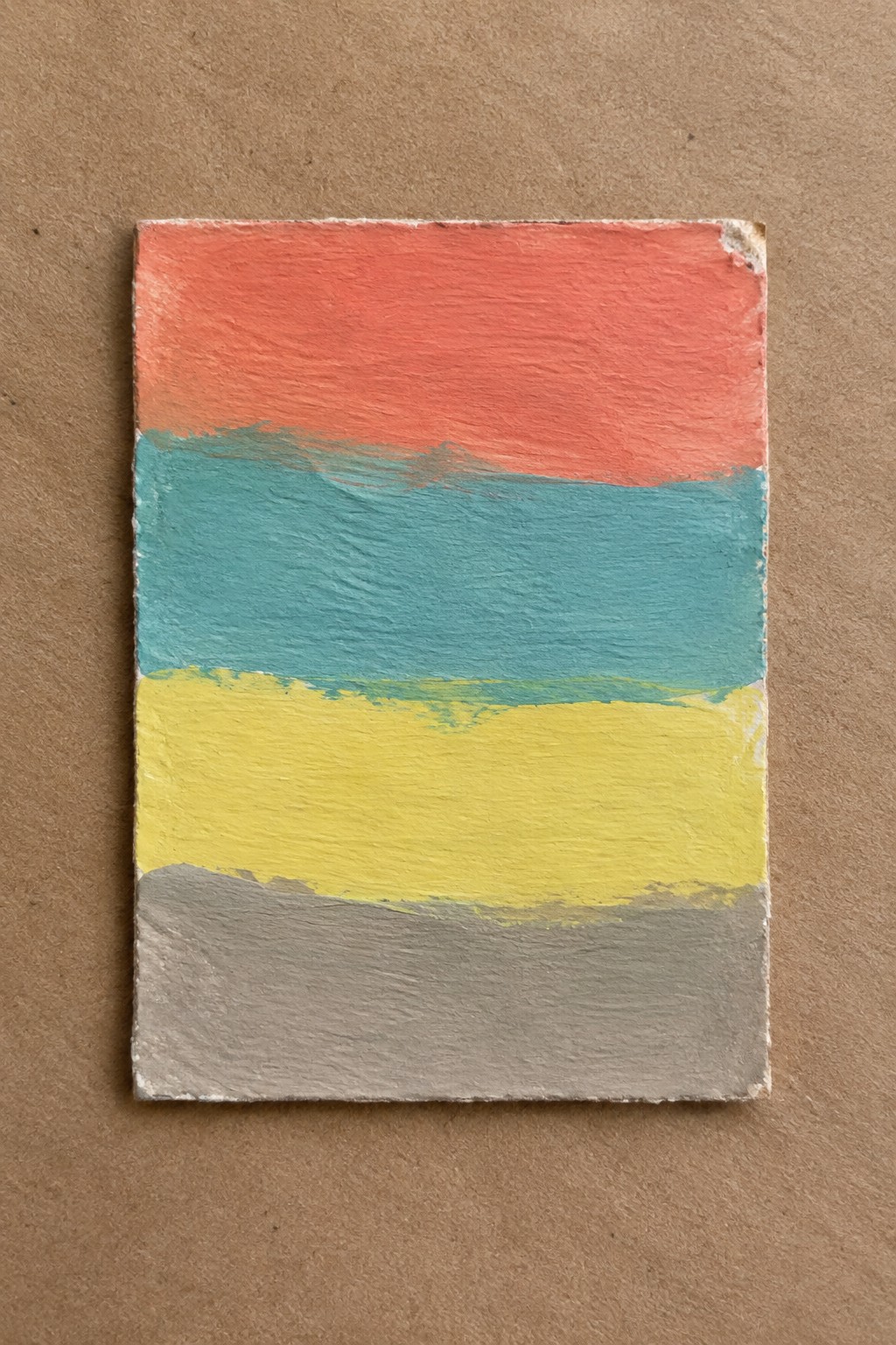 Rectangular painted tile with horizontal bands of red, teal, yellow, and gray.