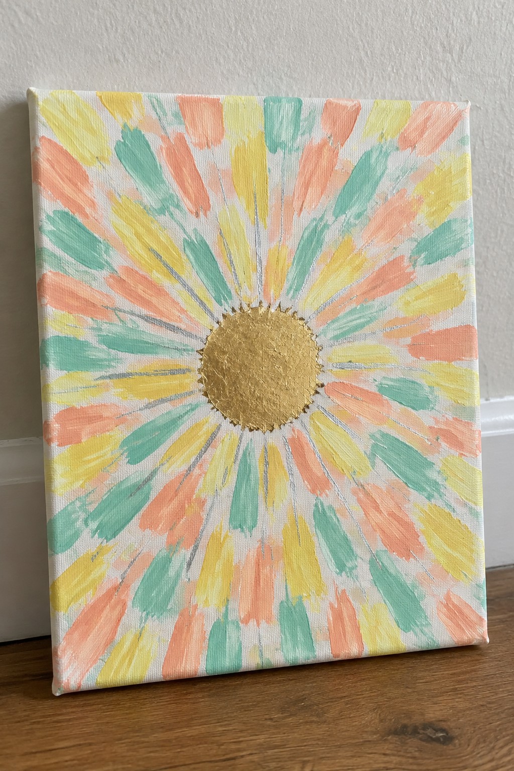 Colorful abstract flower painting with gold center on white canvas.