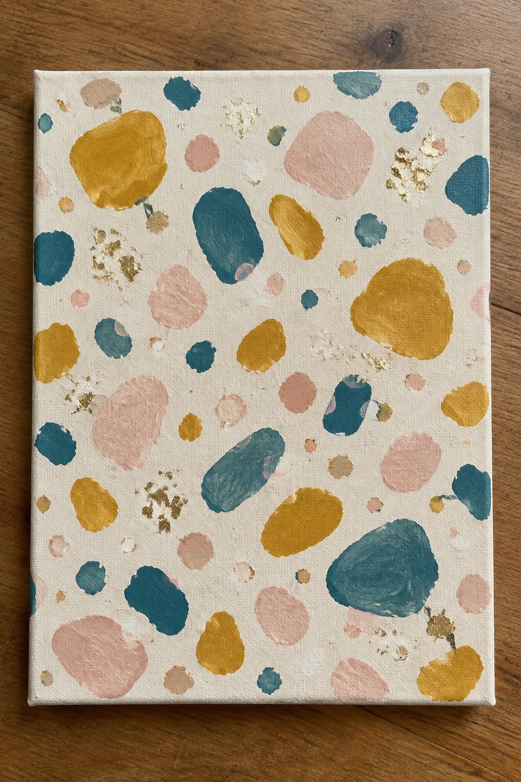 Abstract painting on canvas with teal, mustard, pink blobs and gold leaf on wood.