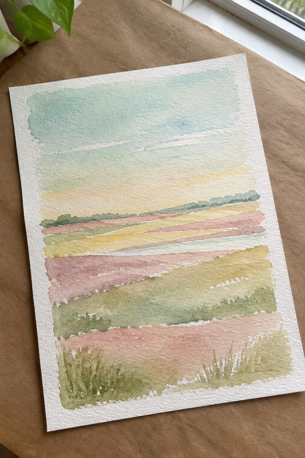 Watercolor landscape with layered pastel fields in pink, green, yellow under blue sky