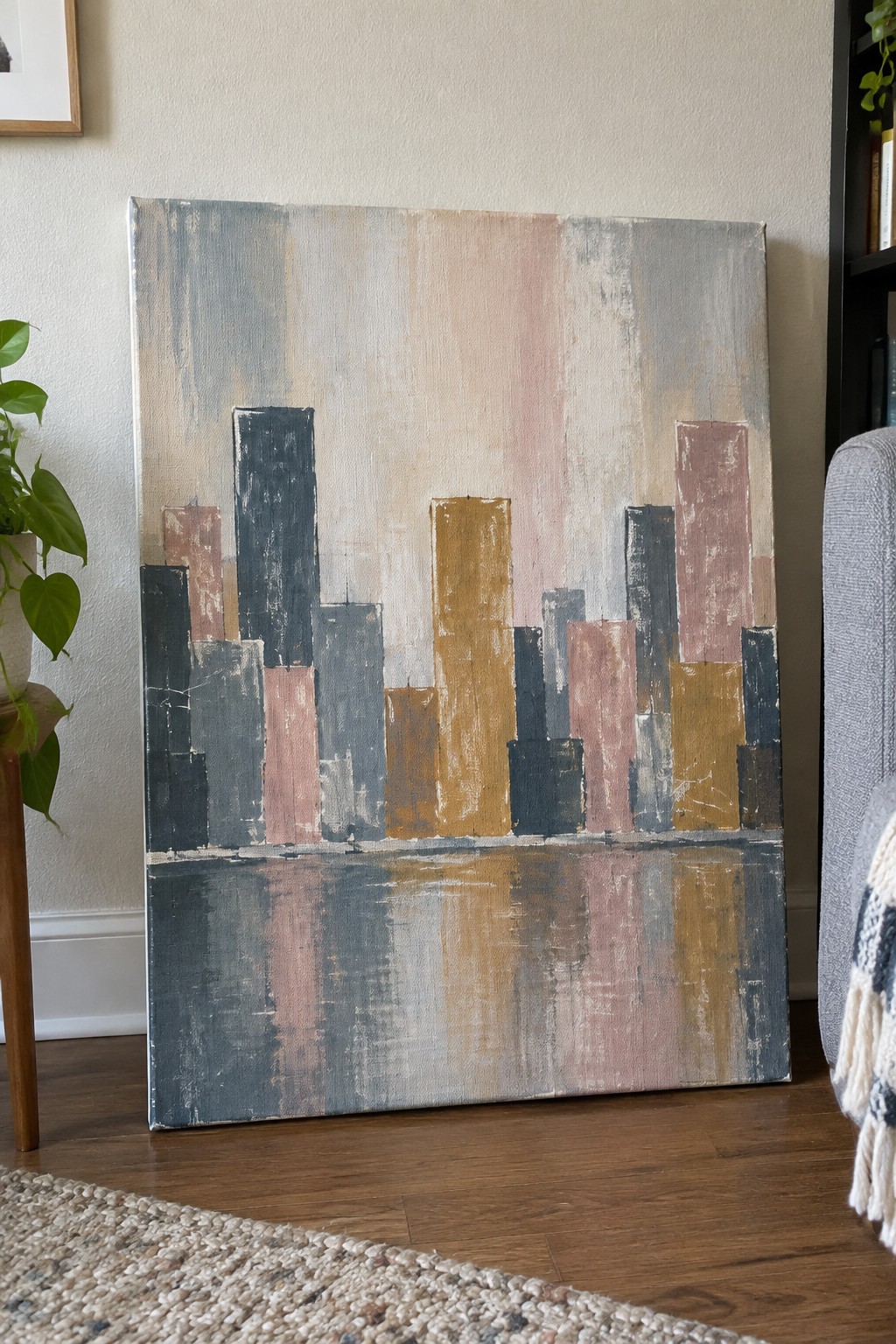 Abstract painting of colorful city skyline with pink, yellow, and gray buildings reflected in water
