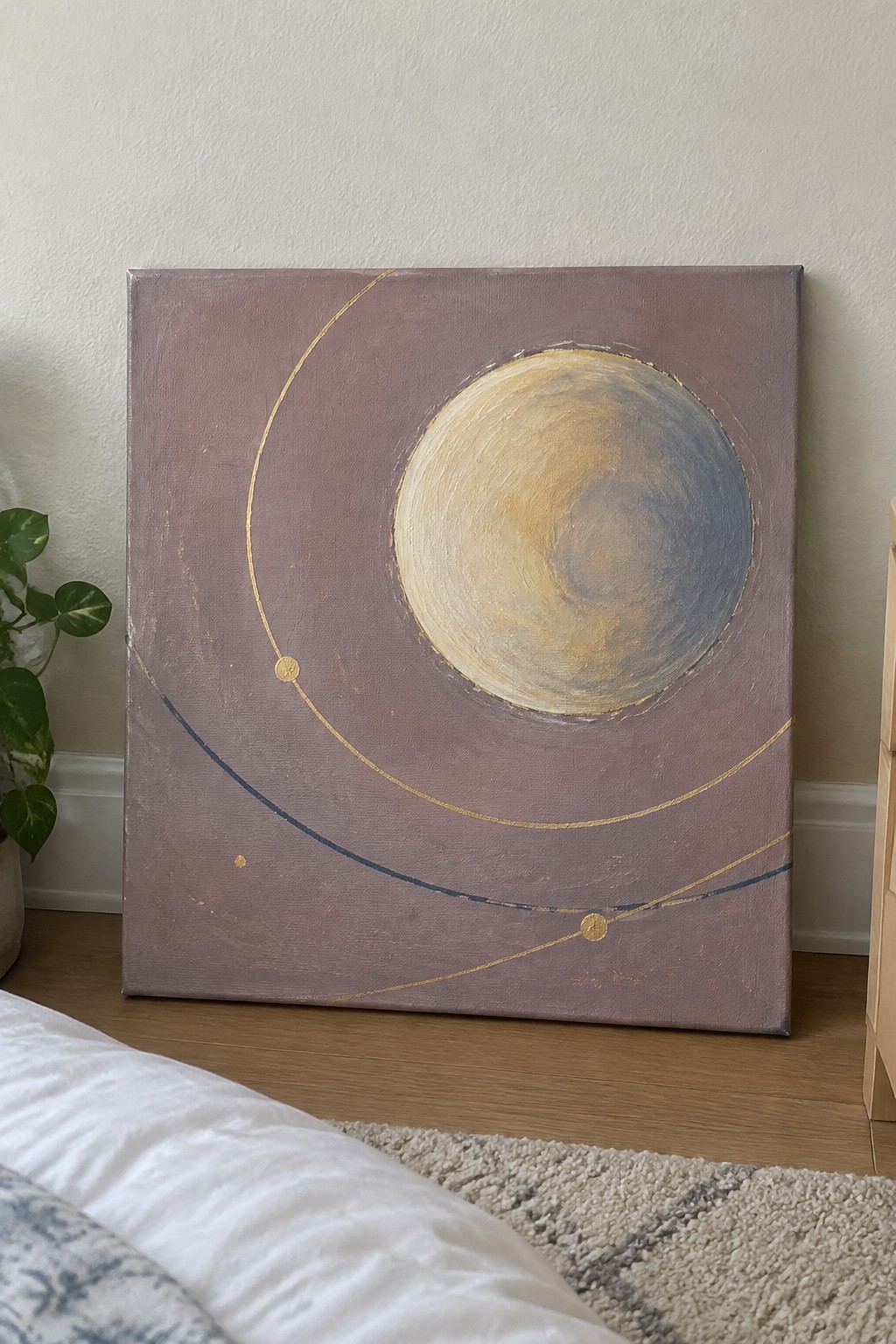 Abstract painting of planet with gold orbital arcs on mauve canvas in bedroom setting
