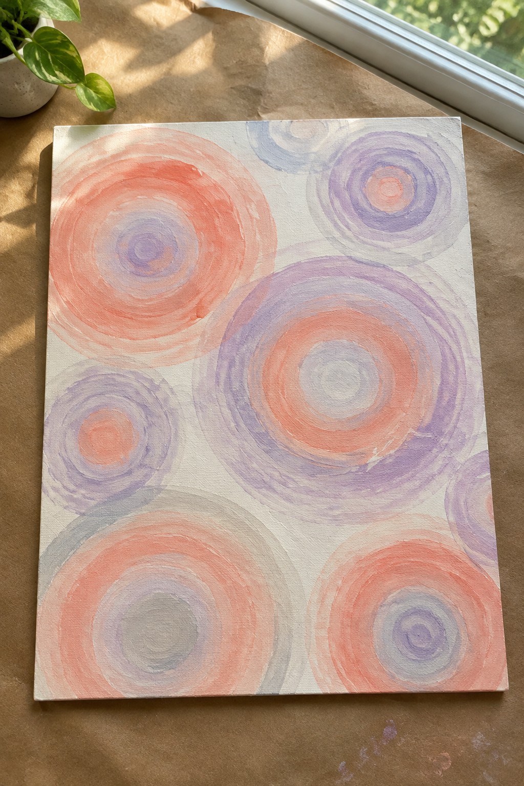 Abstract painting of overlapping coral, purple, and lavender concentric circles on white canvas