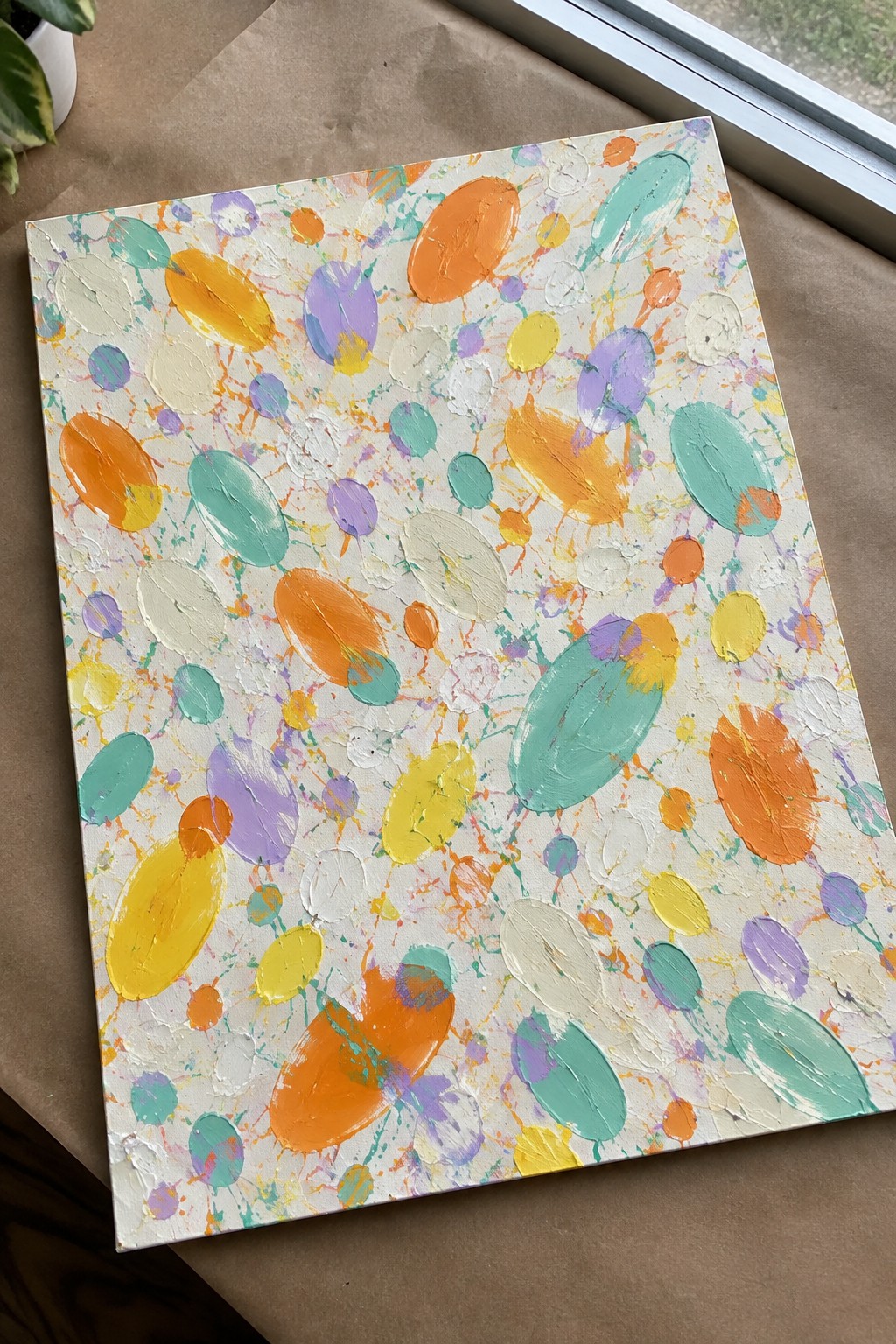 Colorful abstract painting with oval shapes in orange, yellow, purple, and teal on canvas
