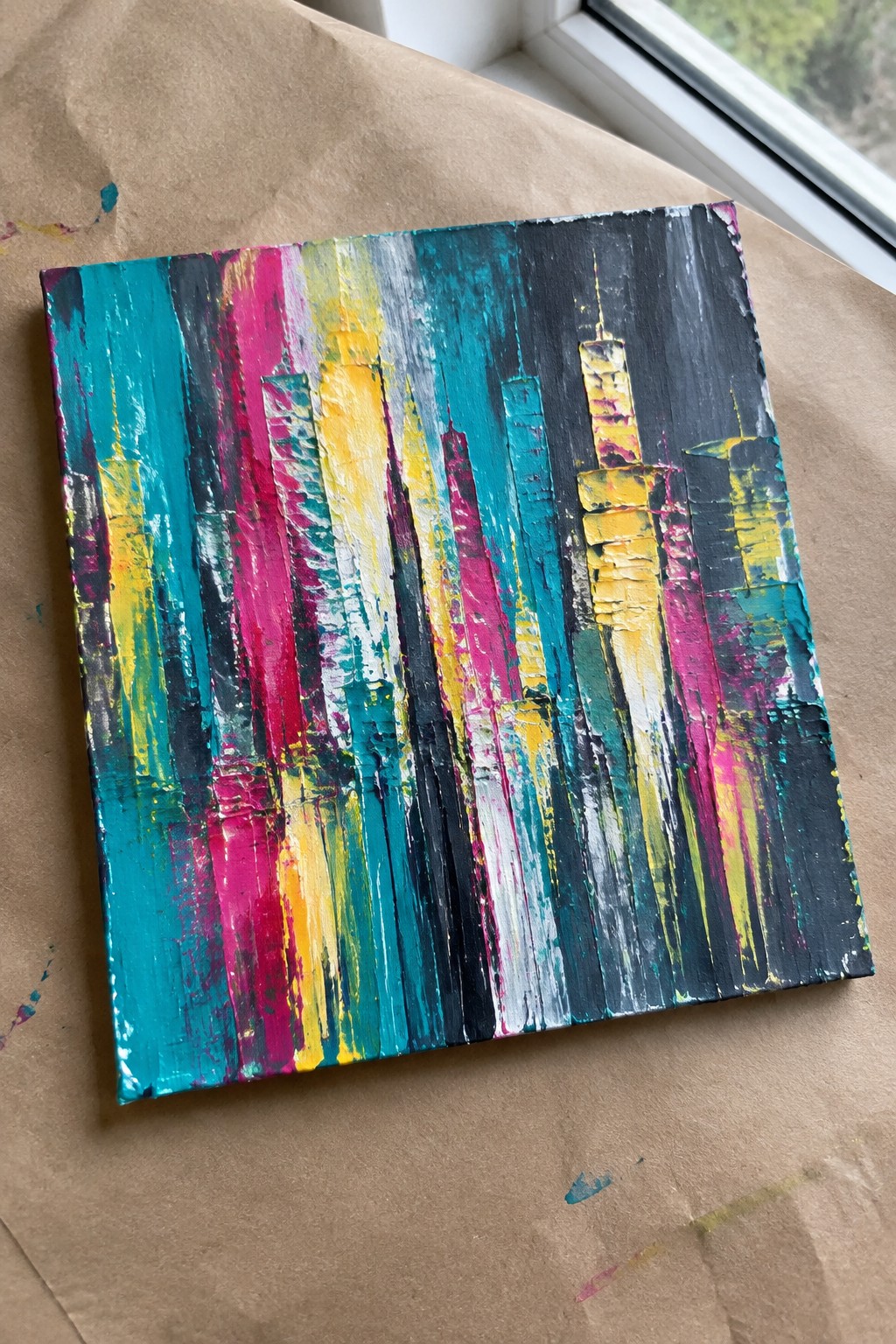 Vibrant abstract cityscape painting with thick colorful vertical brushstrokes on canvas.