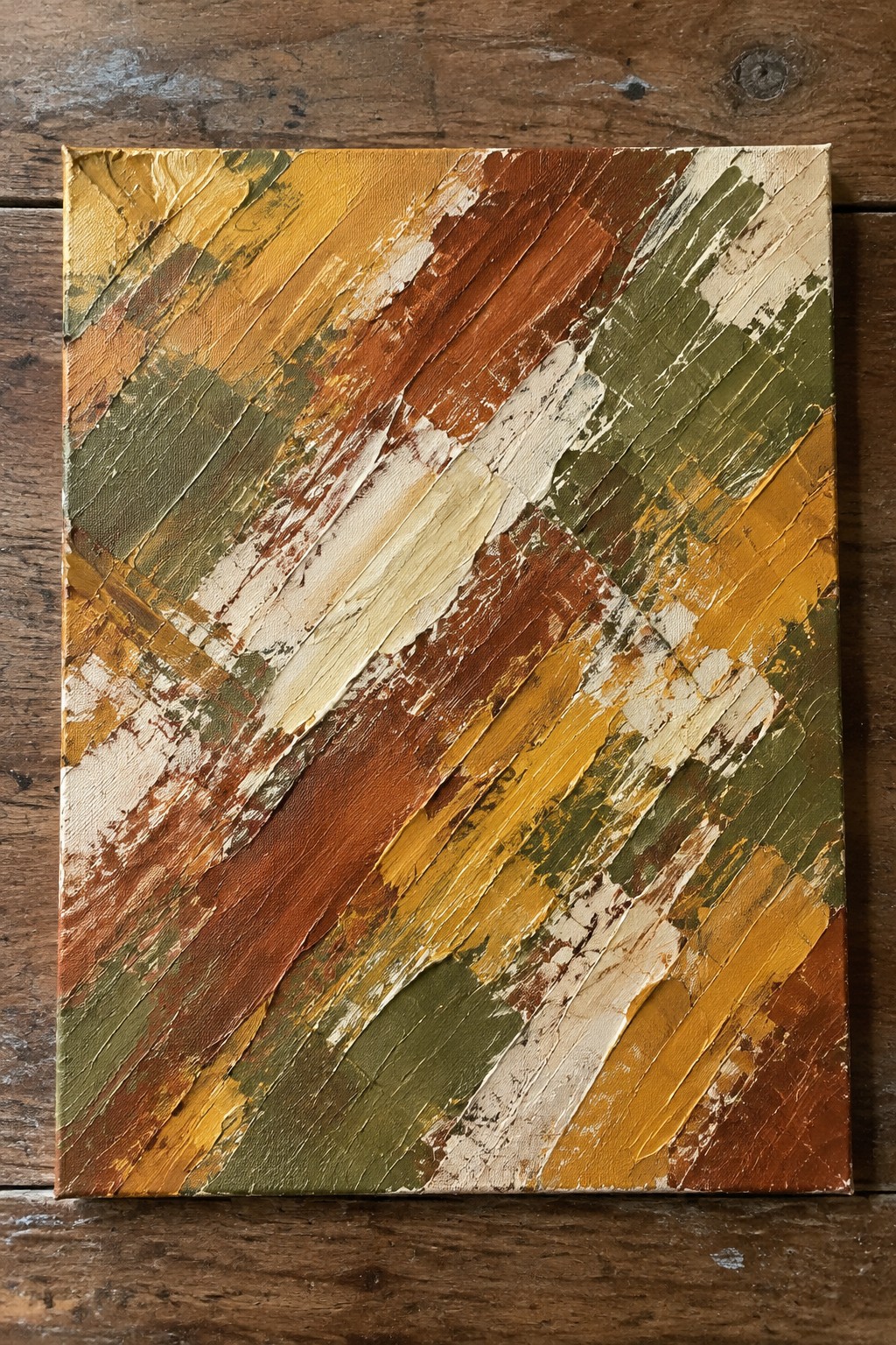Square canvas covered in thick diagonal strokes of orange, brown, yellow, green, and cream paint with heavy palette knife texture.